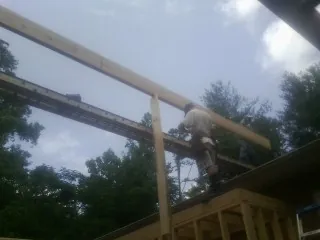 Carpenter setting a ridge beam over a new addition frame — Ice Dam Removal by Roofing Brothers in Locust Fork