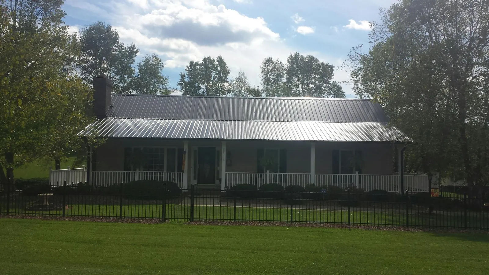 Gray metal roof on a brick ranch with a full width front porch — Gutter Guard Installation work by our crew in Locust Fork