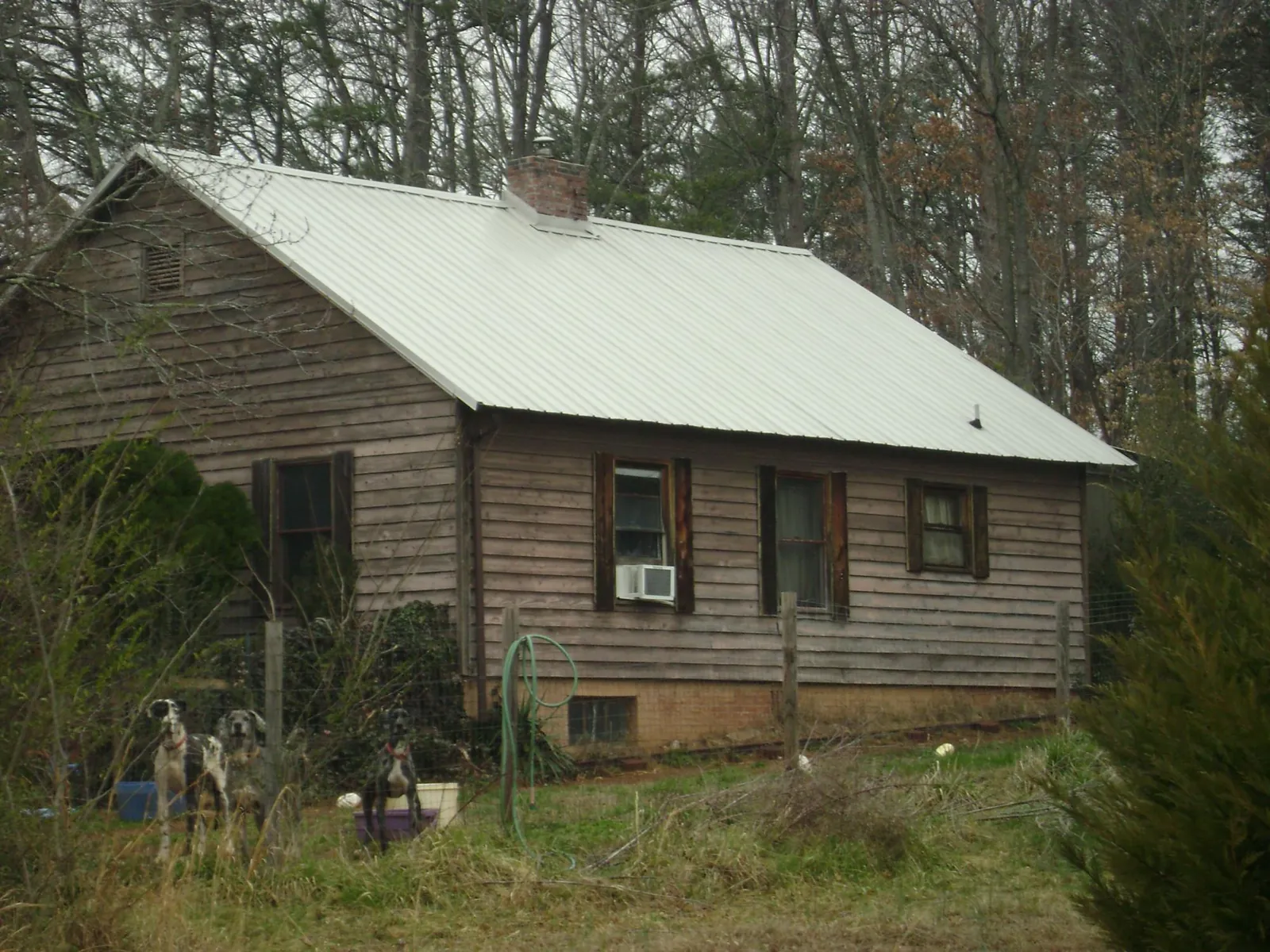 White metal roof on an old wood sided farmhouse, from a Metal Roof Installation job in Locust Fork