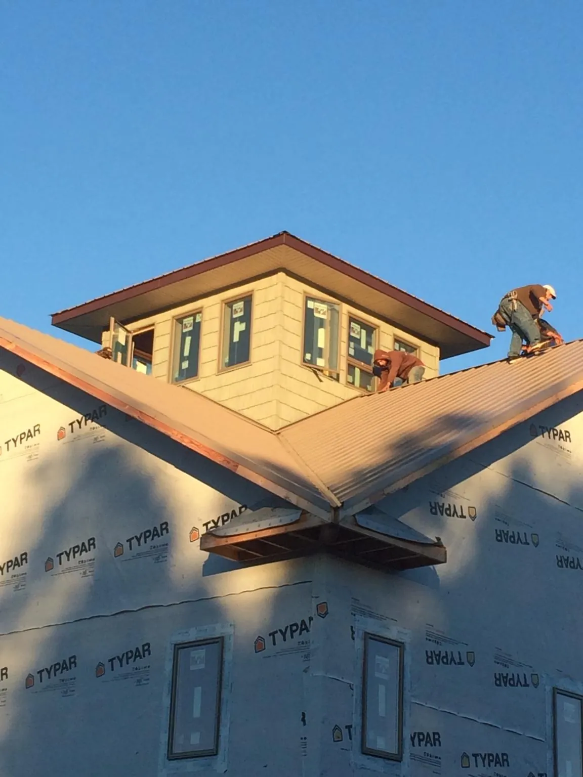 Roofers working around a rooftop cupola on a new metal roof at sunset — Roof Waterproofing in Locust Fork by Roofing Brothers